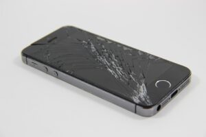 Pantalla del móvil rota con grietas en el cristal sobre fondo oscuro